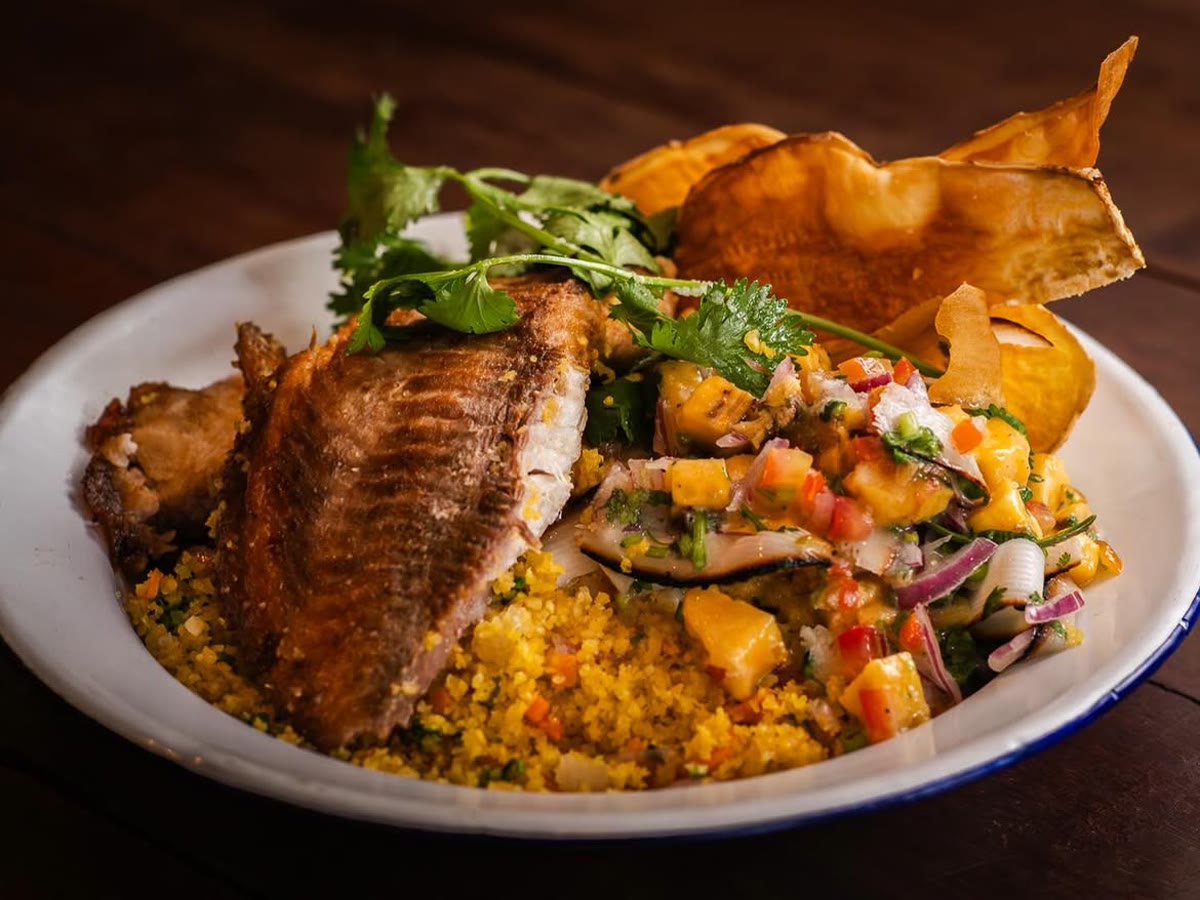 Tilápia suada sobre farofa, com vinagrete e chips de mandioca.