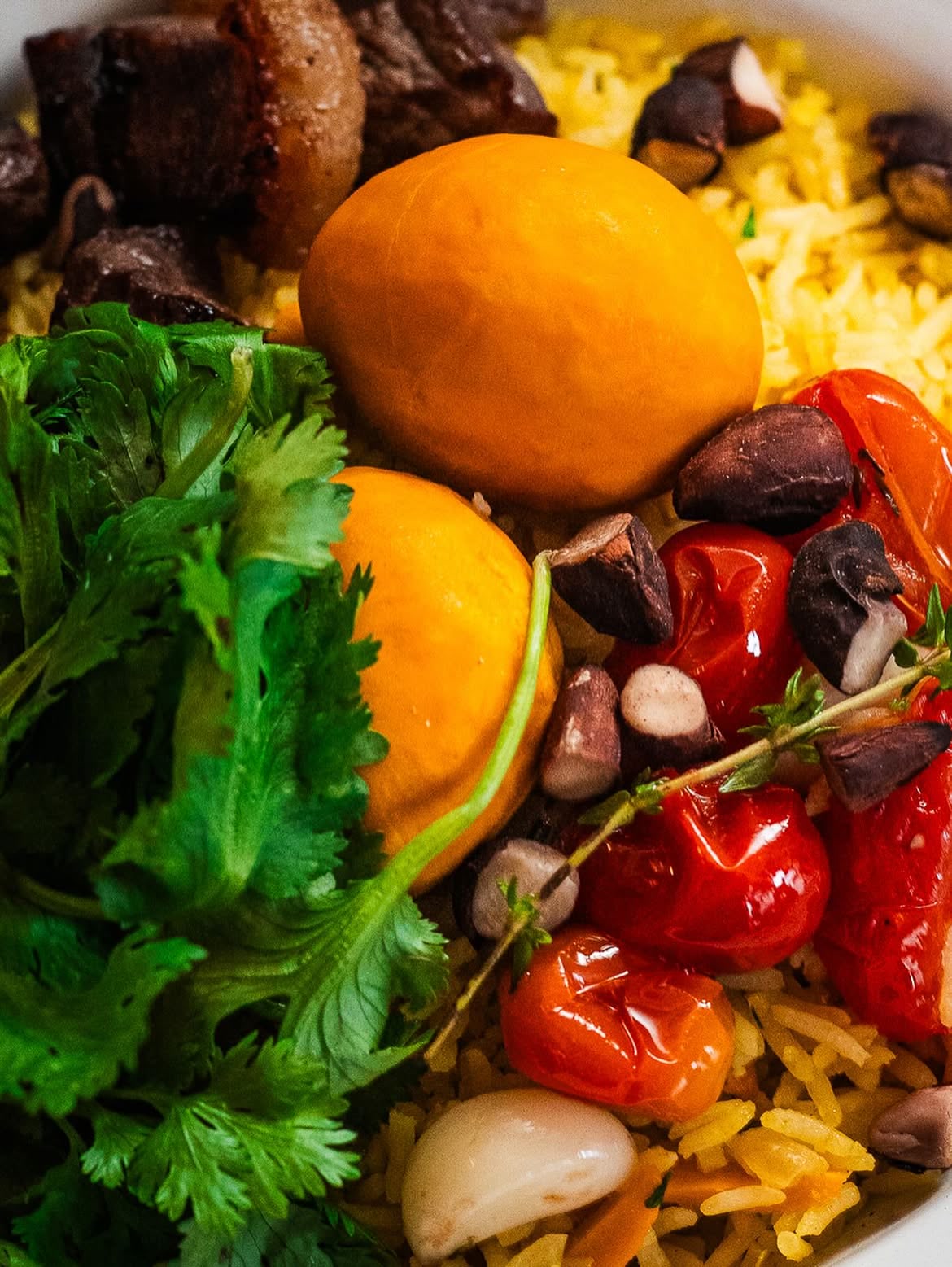 Andu de dois servido no prato esmaltado de borda azul, com arroz de açafrão, carne, gema e tomate.
