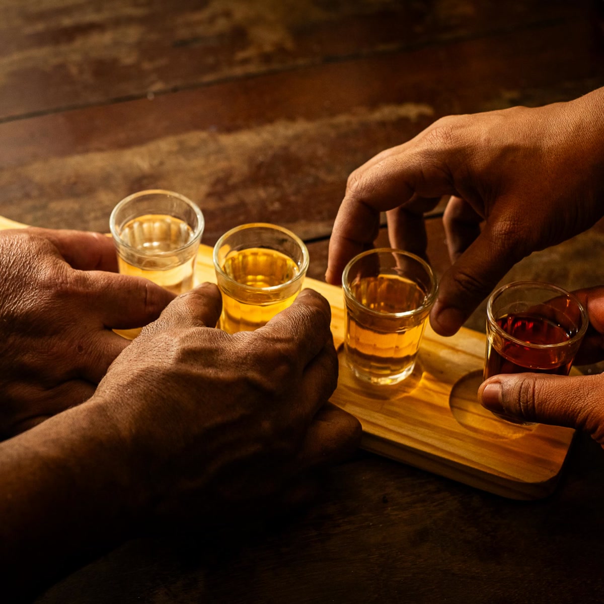 Quatro mãos pegando ao mesmo tempo as doses da régua, na mesa de madeira.